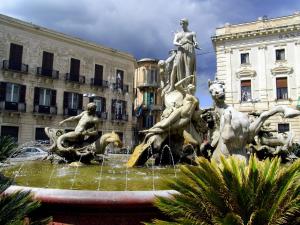 une fontaine avec des statues devant un bâtiment dans l'établissement Residenza Matteotti, à Syracuse