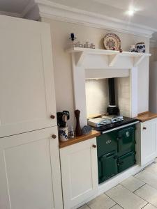 La cuisine est équipée de placards blancs et d'un four vert. dans l'établissement Beautiful, rustic bungalow, à Reydon