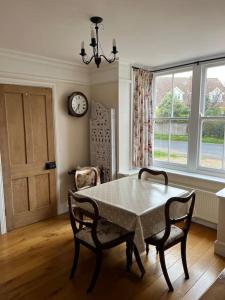 une salle à manger avec une table, des chaises et une horloge dans l'établissement Beautiful, rustic bungalow, à Reydon