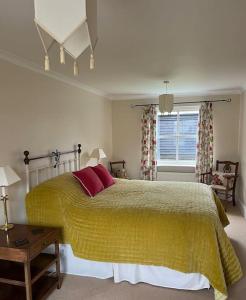 - une chambre avec un lit doté d'une couverture jaune et d'une fenêtre dans l'établissement Beautiful, rustic bungalow, à Reydon