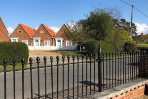 a black fence in front of a row of houses at Beautiful, rustic bungalow in Reydon