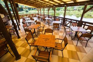 an empty restaurant with tables and chairs and water at Tartak Resort in Pasiky-Zubryts'ki