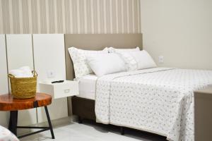 a bedroom with a bed with white sheets and a table at Lukinhas Pousada in Nobres