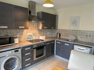 a kitchen with a washing machine and a microwave at Town Centre Apartment in Westport