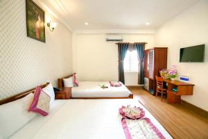 Cette chambre comprend deux lits et une télévision. dans l'établissement Biển Xanh Hotel Quy Nhơn, à Quy Nhơn
