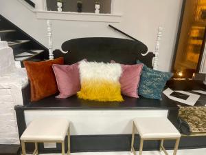 a bench with colorful pillows on it with two stools at Prestige Collection, Hotel Boutique in St. Petersburg