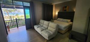 1 dormitorio con cama, sofá y balcón en Pandan Laut Beach Resort, en Kampung Penarik