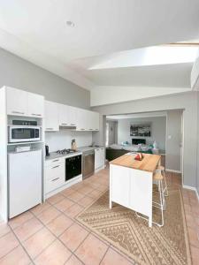 a kitchen with white cabinets and a wooden table at Frangipani in Sydney