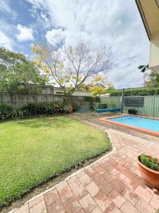 a backyard with a swimming pool and a yard at Frangipani in Sydney