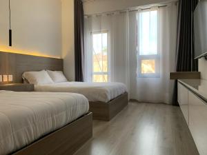 a hotel room with two beds and two windows at Hotel Blanco Pachuca in Pachuca de Soto