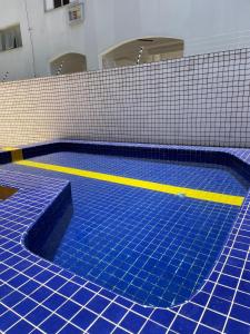 una piscina con azulejos azules y rayas amarillas en Apartamentos Primavera Guarujá en Guarujá