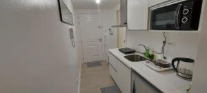 a white kitchen with a sink and a microwave at Azure North San Fernando Pampanga in San Fernando