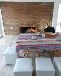 a woman sitting at a table in front of a fireplace at Vivienda en Cuchi Corral in Los Puquios