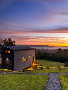 een klein huisje op een heuvel met de zonsondergang op de achtergrond bij La isla Loft in Quellón