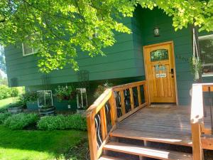 uma casa verde com um alpendre de madeira e uma porta de madeira em Beautiful hideaway at the end of a cul-de-sac in Missoula em Missoula