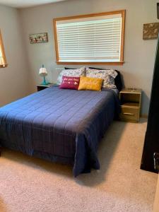 um quarto com uma cama azul com almofadas e uma janela em Beautiful hideaway at the end of a cul-de-sac in Missoula em Missoula