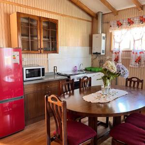 a kitchen with a table and a red refrigerator at Cabañas y Hospedaje Parque los Volcanes in Llanquihue