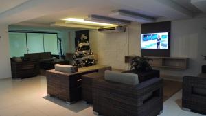 a living room with couches and a flat screen tv at Praia de Tabatinga- Flat do BZ - 2 quartos in Conde