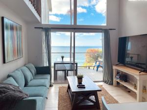 a living room with a blue couch and a large window at OCEAN FRONT Beach HOUSE! Private Stairs to SAND! in Laguna Beach