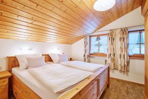 Cama grande en habitación con techo de madera en Haus Kohlpointner, en Oberwössen