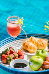 a tray of food with a drink and strawberries and croissants at De'Colore Villa Hoi An in Hoi An
