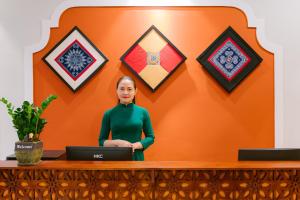 a woman standing behind a desk with a laptop at De'Colore Villa Hoi An in Hoi An