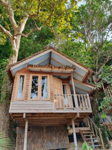 a tree house with a porch and a balcony at Palm Beach Resort Koh Phayam in Ko Phayam