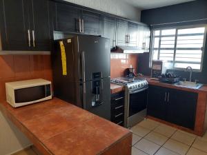 a kitchen with a black refrigerator and a microwave at Casa Camichines in Ciudad Guzmán