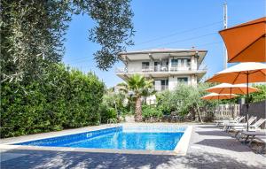 una piscina con sombrilla y un edificio en Cozy Apartment In Santa Venerina With Outdoor Swimming Pool en Santa Venerina