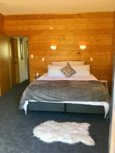 a bedroom with a large bed with a wooden wall at Off the Beaten Track B&B in Canvastown