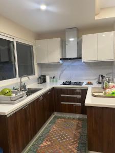 cocina con armarios blancos, fregadero y encimera en Elysium Service Apartment 1203 en Islamabad