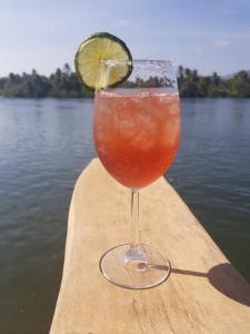 a drink in a glass sitting on the side of a boat at The Hideaway in Kampot