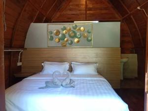 due cigni seduti su un letto con un'immagine di frutta di Ovai Hidden Paradise Resort a Papar