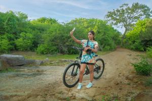 a woman standing next to a bike on a dirt road at Leopard Nest - Glamping in Yala in Yala