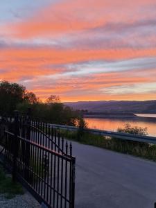 a sunset over a body of water with a fence at Apartament z kominkiem nad Jeziorem Czorsztyńskim in Frydman