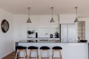 a kitchen with a counter with three bar stools at Anchored@Bicheno - Ohmyview! in Bicheno