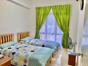 2 Betten in einem Zimmer mit grünen Vorhängen und einem Fenster in der Unterkunft Marina Cove, Lumut in Lumut