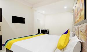 a bedroom with a white bed with a yellow pillow at Itsy By Treebo - Shashwat in Gorakhpur