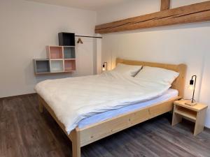 1 dormitorio con 1 cama grande con sábanas blancas en Apartmány na mlýně, en Nové Město na Moravě