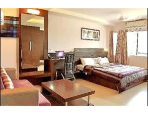 a bedroom with a bed and a desk and a couch at Hotel Pearl,Indore in Indore