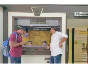 dos hombres parados frente a una puerta de cristal en Hotel Pearl,Indore en Indore