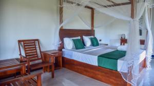 - une chambre avec un lit à baldaquin et une chaise dans l'établissement Sigiriya Paradise Inn, à Sigirîya