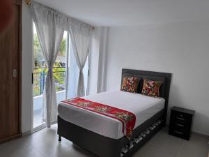 una camera da letto con un letto e una grande finestra di Travelu Guatape Apartamento a Guatapé