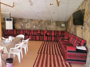 a restaurant with red chairs and tables and a television at The Wadi Inn in Al Ḩamrāʼ