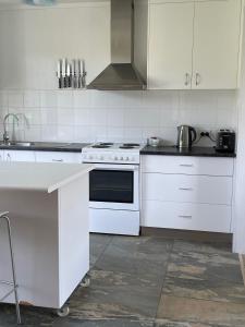 a white kitchen with a stove and a sink at Sisters Beach House in Sisters Beach