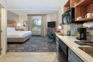 a hotel room with a bed and a kitchen at Candlewood Suites Idaho Falls, an IHG Hotel in Idaho Falls