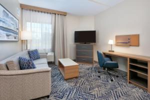 a hotel room with a couch and a desk and a television at Candlewood Suites Idaho Falls by IHG in Idaho Falls
