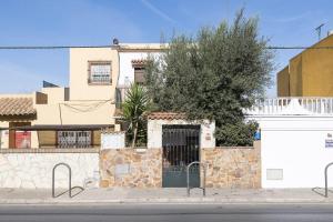 um edifício branco com uma parede de pedra e uma árvore em Casa Del Olivo em Algeciras