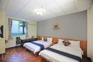 a bedroom with two beds and a desk and a window at Pulicity Villa B&B in Puli