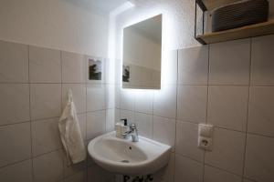 een witte badkamer met een wastafel en een spiegel bij Modernes & zentrales Micro-Apartment in Boppard